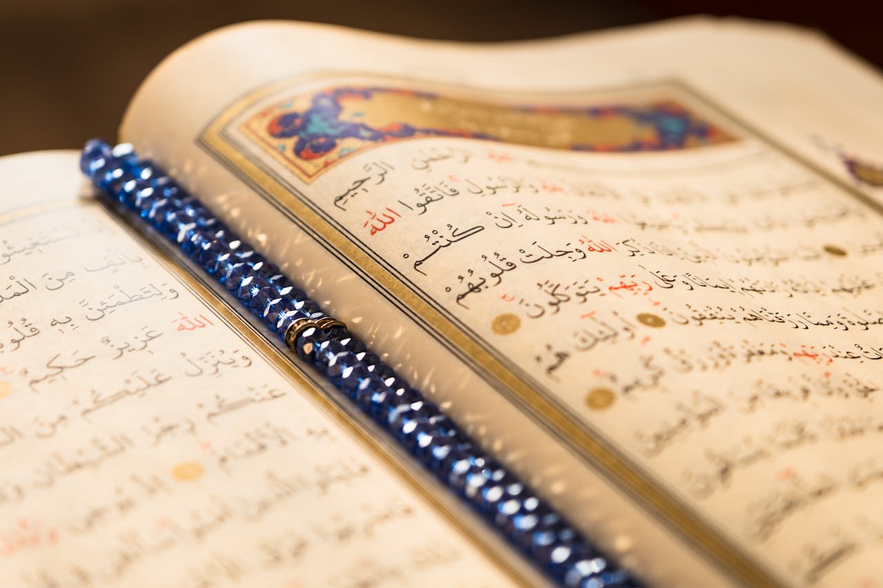 hero-gallery-02 Detailed image of an open Quran with an ornate blue beaded bookmark, showcasing sacred script.