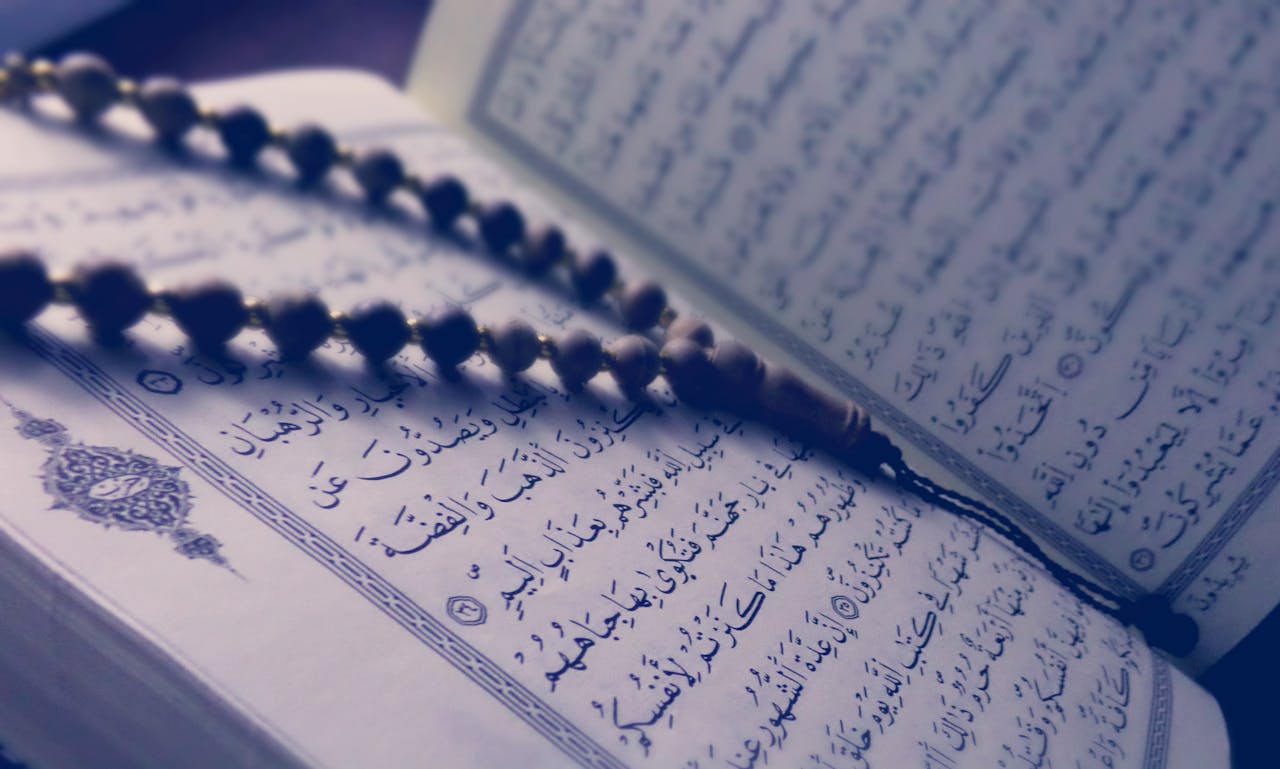 hero-gallery-04 A close-up of prayer beads resting on an open Quran page, depicting Islamic faith and worship.