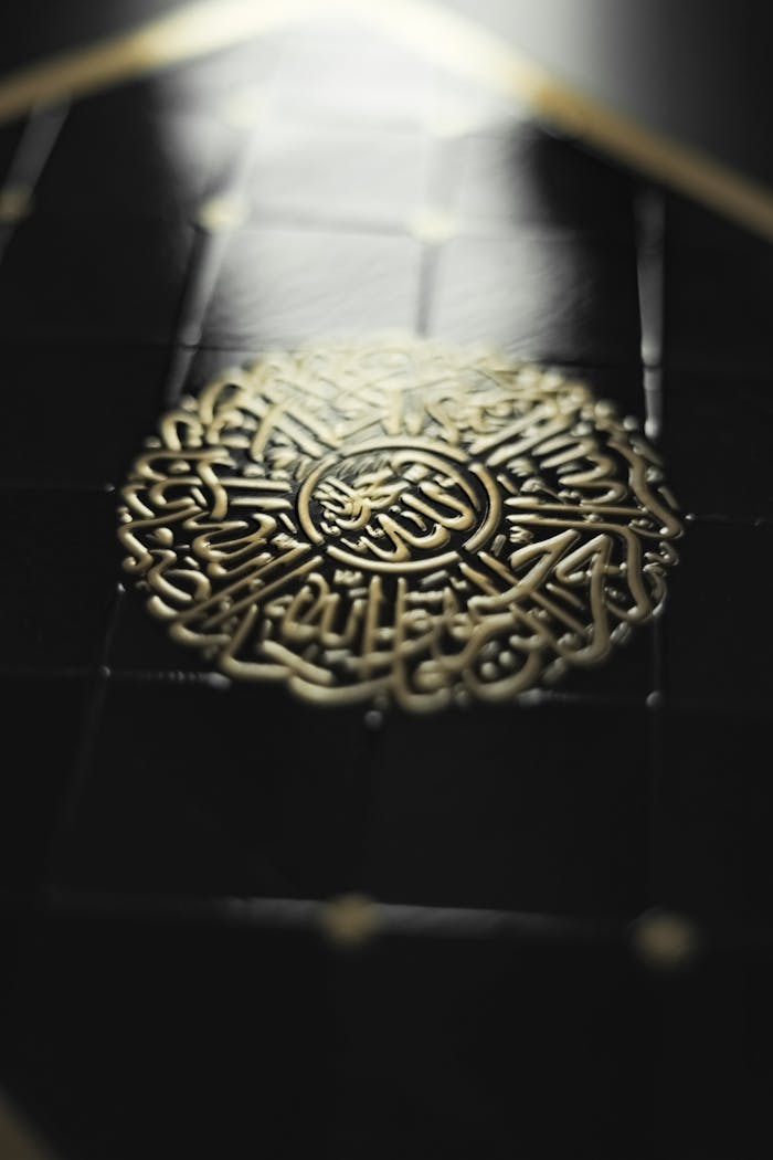 about-img Close-up of an ornate Islamic decorative element with golden calligraphy and intricate patterns.