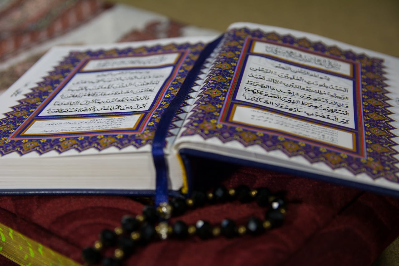 why-choose-us-img Open Quran with prayer beads on a richly textured fabric, highlighting Arabic calligraphy and spirituality.